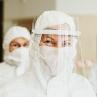 编辑人员坐在书桌前对照屏幕核对物流节点时间戳，桌面摆放纸笔与打印出的运单表格，暖色台灯照明